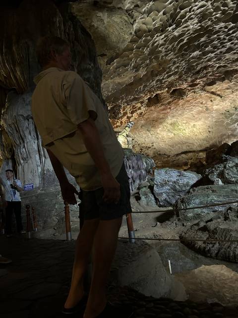 Tourist exploring a dimly lit cave with formations.