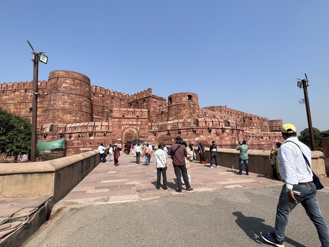View towards a large historic fort with visitors walking towards it.
