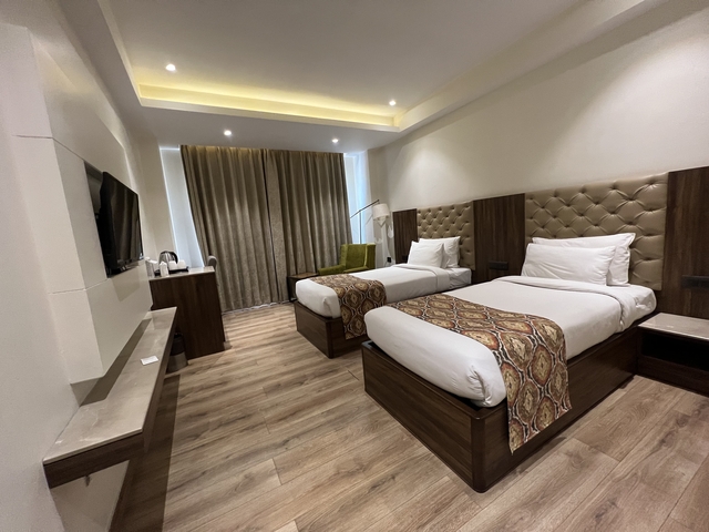       Modern hotel room with twin beds and decor.
  