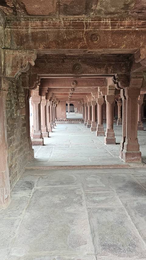 Interior corridor with columns and stone flooring.