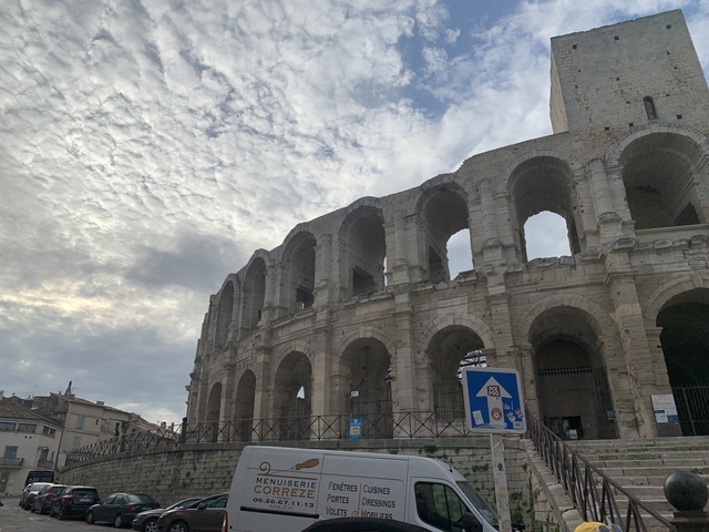 Exterior of a historic coliseum with cloudy skies.