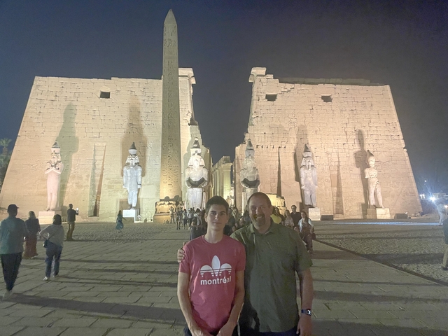 People posing in front of a lit ancient temple at night.