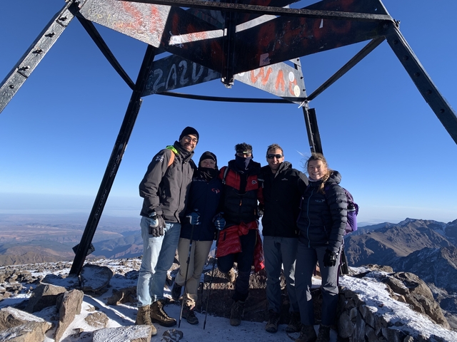Group of people at the peak of a snowy mountain.