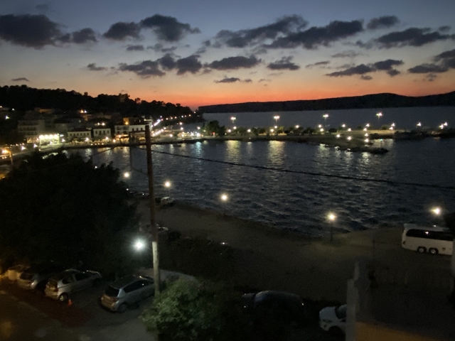 Evening waterfront view with lights reflecting on water.
