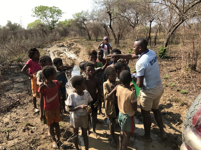       A group of children and an adult in a rural area.
  