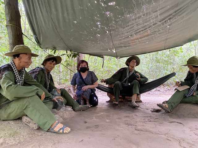Person sitting with mannequins in a military setting.