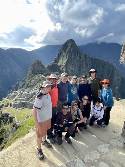       Group of people posing with Machu Picchu in the background.
  