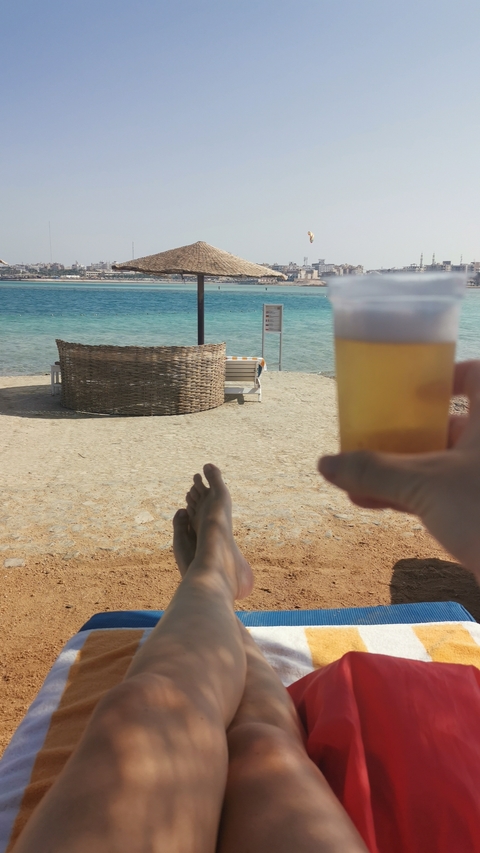 Feet and a drink on a beach with ocean view.