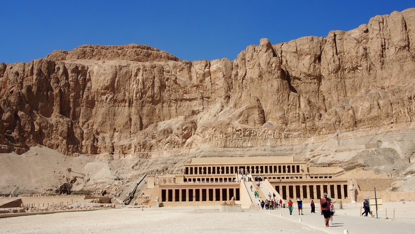       Temple complex with tourists walking toward it.
  