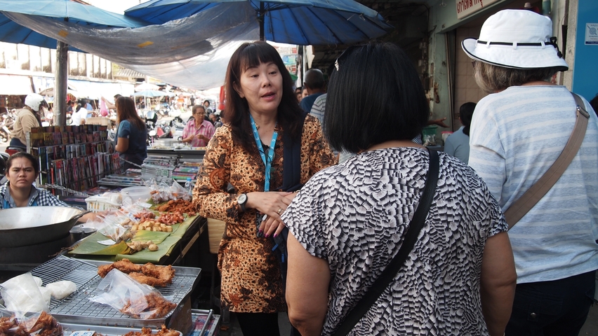 People at a busy market stall with various food items.