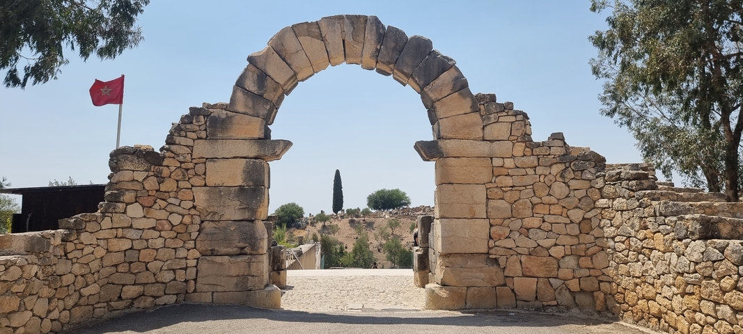 Stone archway marking an ancient site with trees.