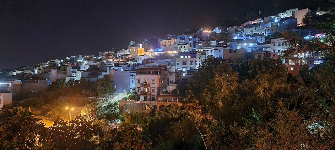 Night view of a hillside city with lit buildings.