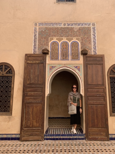       Person standing at the entrance of a decorative Moroccan building.
  