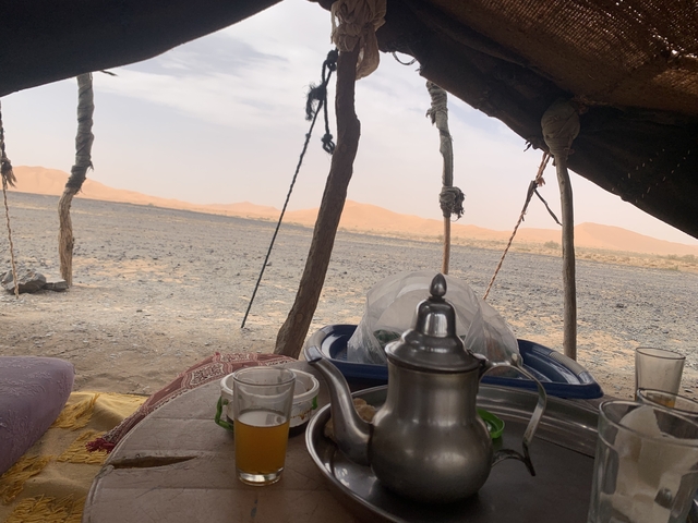       Desert landscape with a tent and tea setup.
  