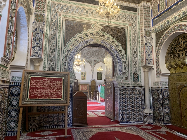       Intricate interior of a Moroccan building showing arches and mosaic tiles.
  
