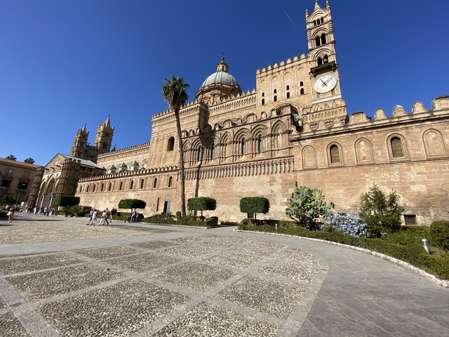       Palermo Cathedral with people walking around the historical site.
  