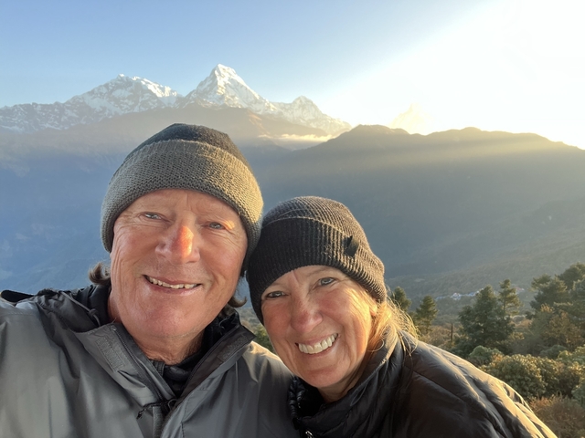 Couple taking a selfie with the Himalayas in the background during sunrise.