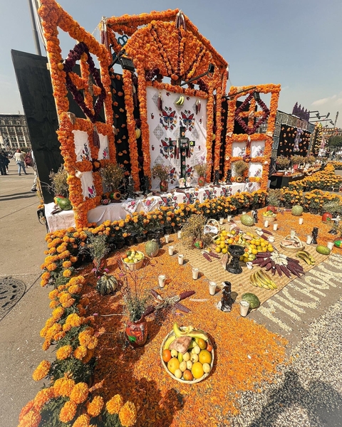       Elaborate Day of the Dead altar with bright marigold flowers and fruit.
  