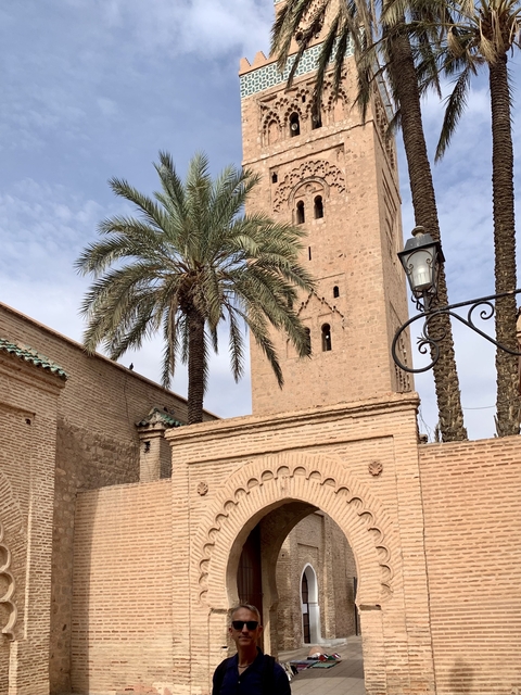       Tall stone mosque minaret surrounded by palm trees.
  