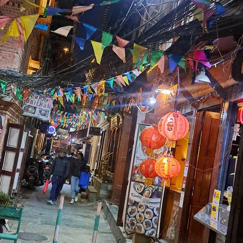 Colorful flags and lanterns in a night market setting.