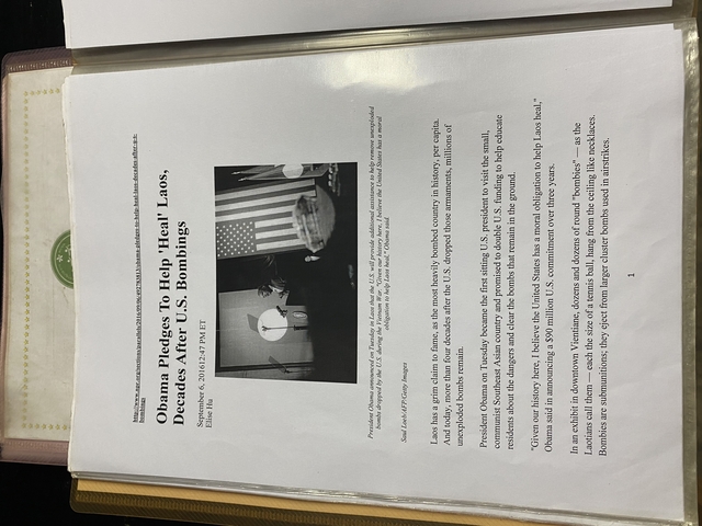       Printed article about U.S. bombings in Laos mounted on a wall.
  