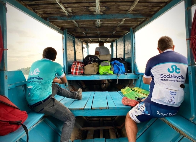       Cyclists on a blue-painted open-air vehicle on a road trip.
  