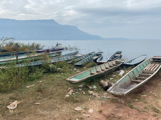       Boats lined along a grassy bank with mountains in the background.
  