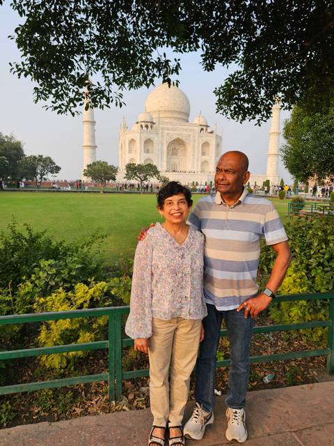 Two people posing with the Taj Mahal in the background.