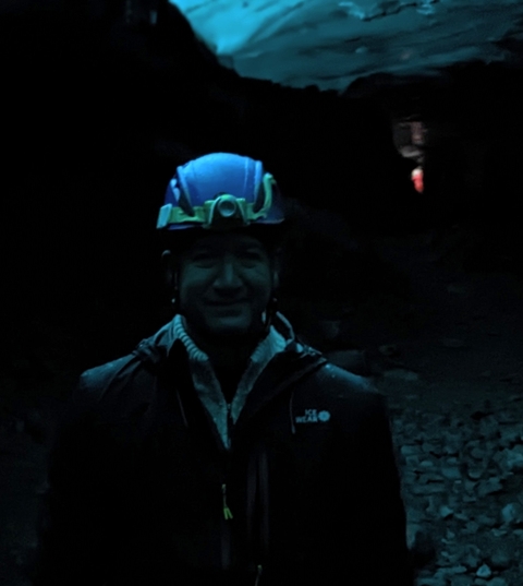 Portrait of a person wearing a helmet in a dark setting.
