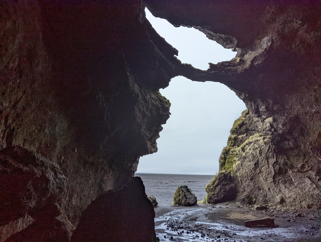 Natural rock formation with a view of the beach and sea.
