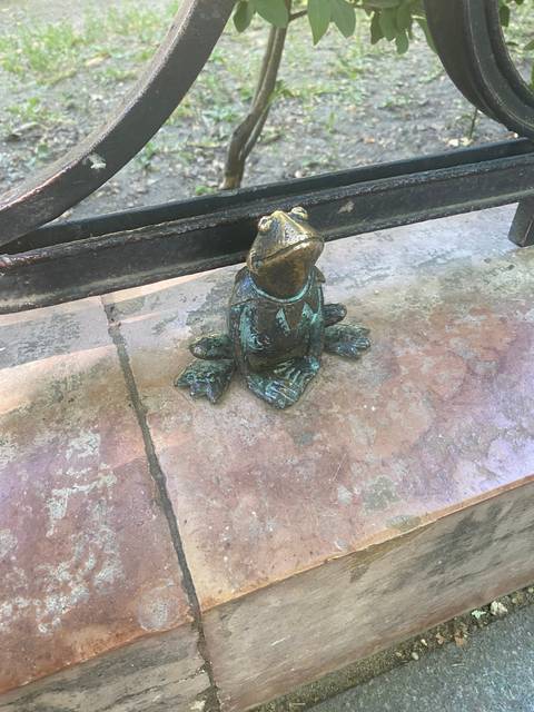 Small frog sculpture on a bench.