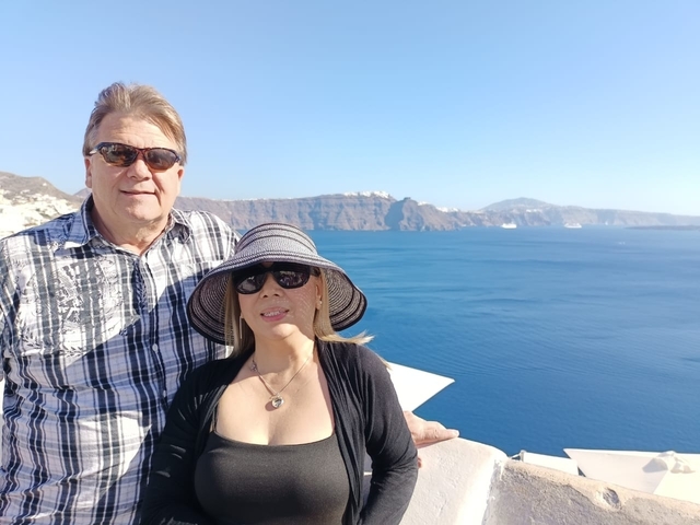 A couple posing with a sea and cliffs in the background.