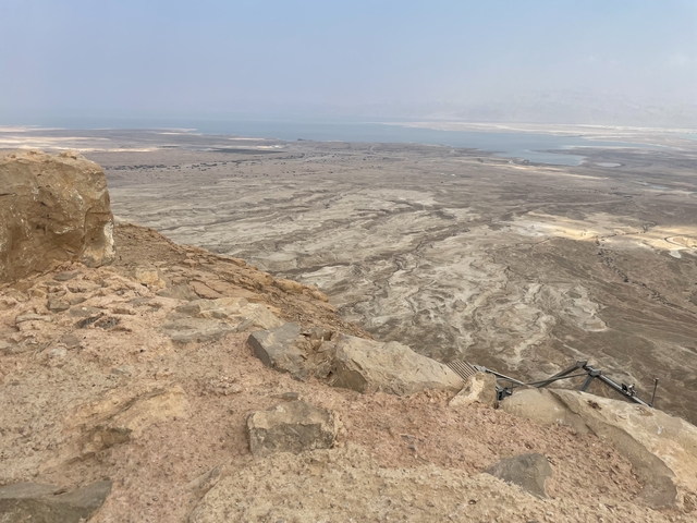       A barren and rocky desert landscape with distant water.
  