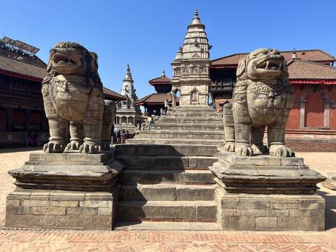       A temple with grand stone staircases and lion statues.
  