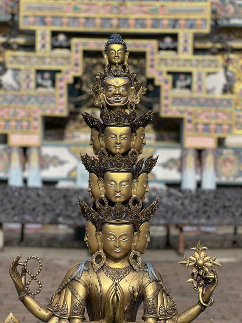       A golden multi-faced deity statue with elaborate carvings.
  