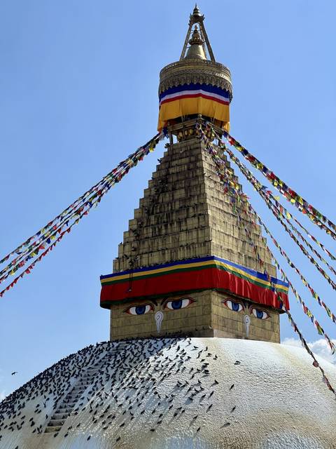       A large stupa with prayer flags and large painted eyes.
  