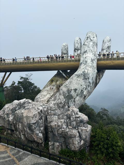 Golden Bridge with tourists, unique hand-shaped supports.
