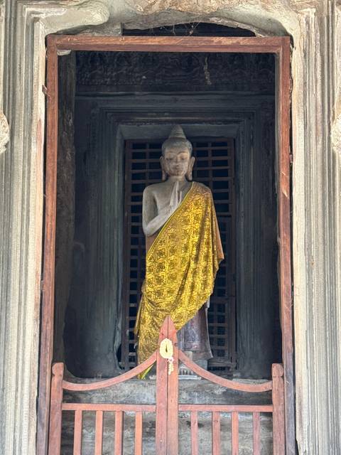       Statue draped in a golden cloth inside a temple.
  