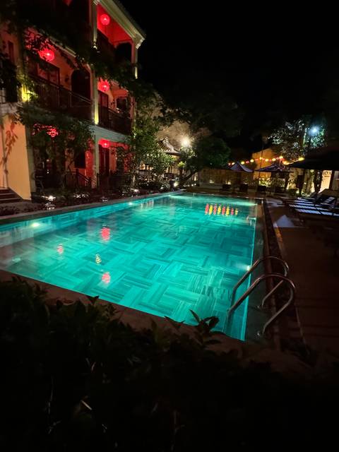       Swimming pool at night with colorful lanterns.
  