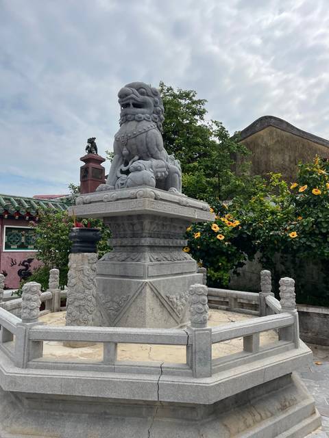 Stone lion statue on a decorated pedestal.