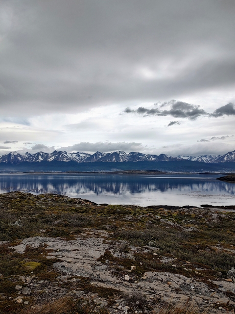       Mountain range with snow caps reflected in a calm lake.
  