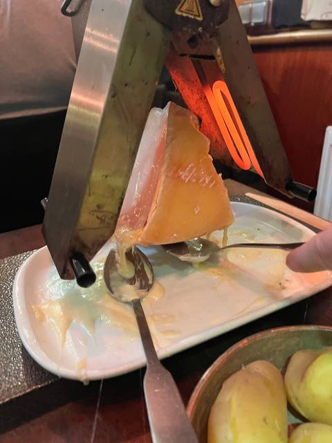       Side view of a dish with melted cheese and utensils.
  