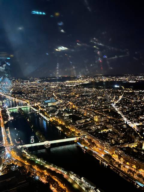      Upside-down panoramic night view of a city with river and lights.
  