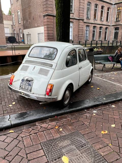       Side view of a classic car parked on a brick street.
  