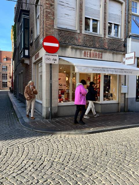       Upside-down view of people walking past a chocolate shop.
  