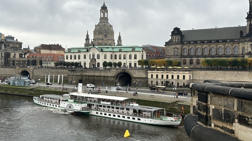       River with historic buildings and a paddle steamer.
  