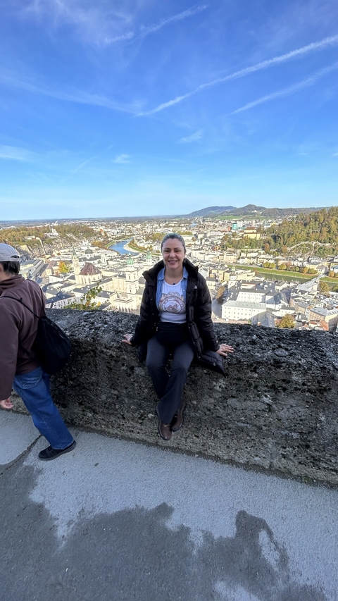       Person sitting with Salzburg view in the background.
  