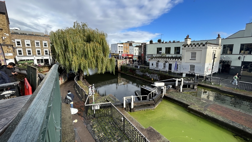       Outdoor market beside a canal in a city setting.
  