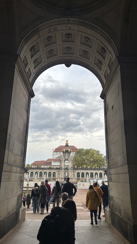       View of distant building with ornate spire through an archway.
  