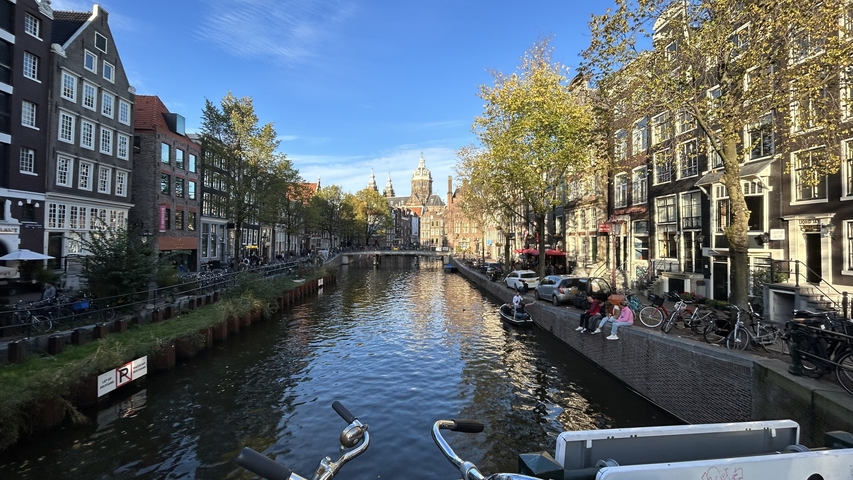       Amsterdam canal with bicycles and historic buildings.
  